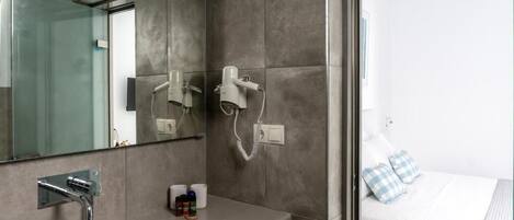 Un baño moderno con un espejo grande, un lavamanos y dos secadores de pelo fijados en la pared.