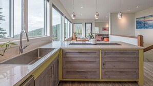 Una cocina moderna con ventanas amplias, una isla central e iluminación colgante.