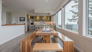 Una cocina moderna con una isla central, bancos de madera y ventanas amplias que ofrecen vistas.