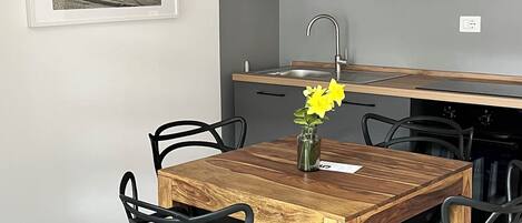 Una cucina moderna con mobili grigi, un tavolo da pranzo in legno, sedie nere e una lampada a sospensione.