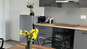 Cocina moderna con armarios grises, encimera de madera y horno empotrado. Un jarrón con flores amarillas sobre la mesa de comedor.