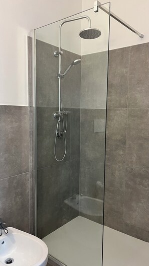Comfort appartement | Badkamer | Een douche, een haardroger, een bidet, handdoeken