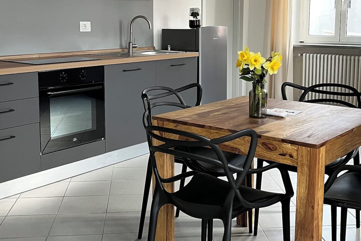 Una cocina moderna con armarios grises, una mesa de comedor de madera y sillas negras.