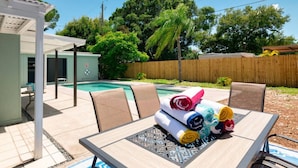 A backyard with a pool, a covered patio, and a table with rolled towels. - Perfect Location for Sports and Concert Venues! - La Cabina (Tampa)