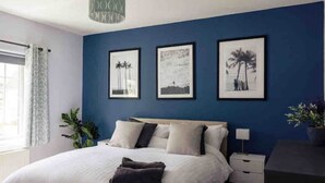 A bedroom with a bed, a nightstand, a desk, and three framed pictures on the wall. - Beautiful seaside retreat close to North Devon's white sandy beaches! (Wrafton)