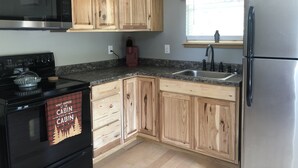 A kitchen with wooden cabinets, a stainless steel refrigerator, a microwave, a stove, and a sink.