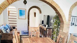 A rustic dining area with a wooden table and benches, surrounded by brick arches and a tiled floor. - Townhouse in the vibrant old town (Tarifa)