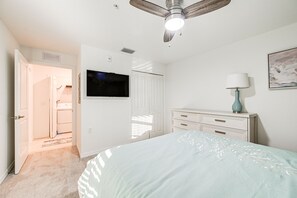 Relax in this serene bedroom with a large bed, flat-screen TV, and ceiling fan.