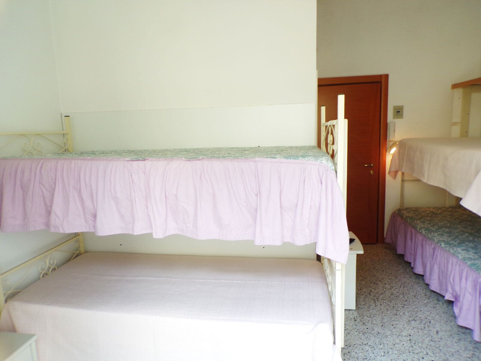 A dormitory room with two bunk beds and a single bed.