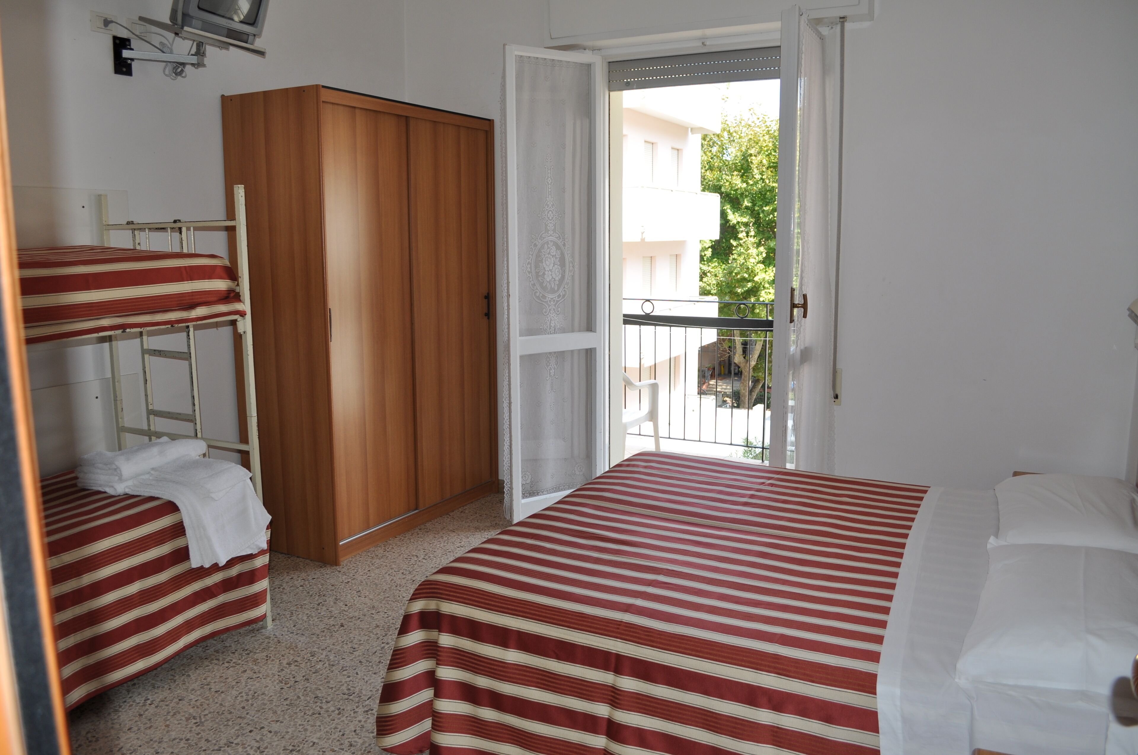 Una habitación con dos camas, un armario y un balcón.