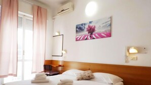 Habitación de hotel con cama, almohadas, una silla, un escritorio y un cuadro en la pared.