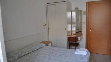 Ein Schlafzimmer mit Bett, Schreibtisch, Stuhl, Kleiderschrank und einer Tür.