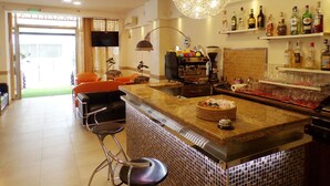 Zona de bar con una máquina de café, una lámpara colgante y estantes con botellas.