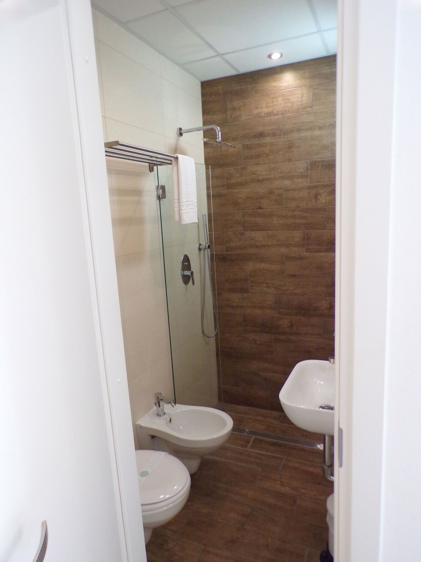 A modern bathroom with a glass-enclosed shower, two sinks, and a wooden wall.