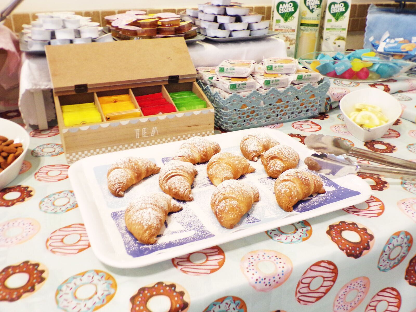 Une table de buffet proposant des pâtisseries, du thé et divers autres aliments.