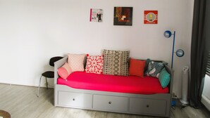 A bedroom with a bed, a standing fan, and wall art. - Limoges,,belle vue ! (Limoges)