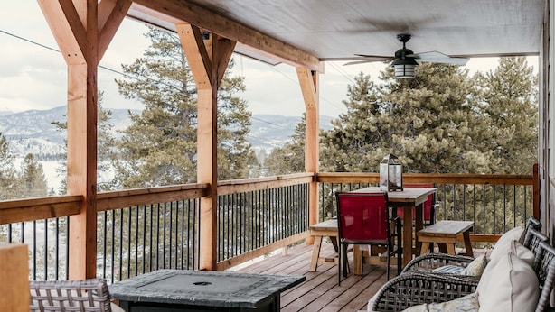A wooden deck with a table, chairs, and a wicker sofa overlooking a snowy landscape. - Discover Lake Granby steps away (Granby)