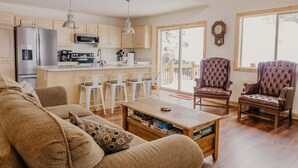A modern kitchen with stainless steel appliances, a dining area with white chairs, and a cozy living room with a sofa and a coffee table. - Discover Lake Granby steps away (Granby)