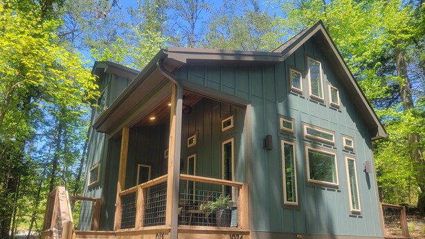 A two-story house with a covered porch and a stone foundation. - The Stone - Modern Cabin on 40+ acres, 10 mins from Tryon Equestrian Center TIEC (Rutherfordton)