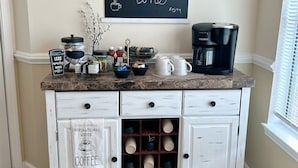 Une cuisine équipée d’un coin café, comprenant une machine à café, des tasses et un panneau indiquant « Pause café ».