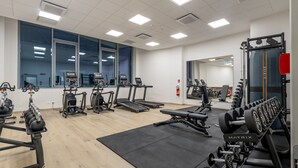 Un gimnasio con cintas de correr, máquinas elípticas y equipo de levantamiento de pesas.