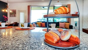 Colazione servita con pasticcini e tazze su un piano di lavoro in granito in una camera d'albergo moderna.
