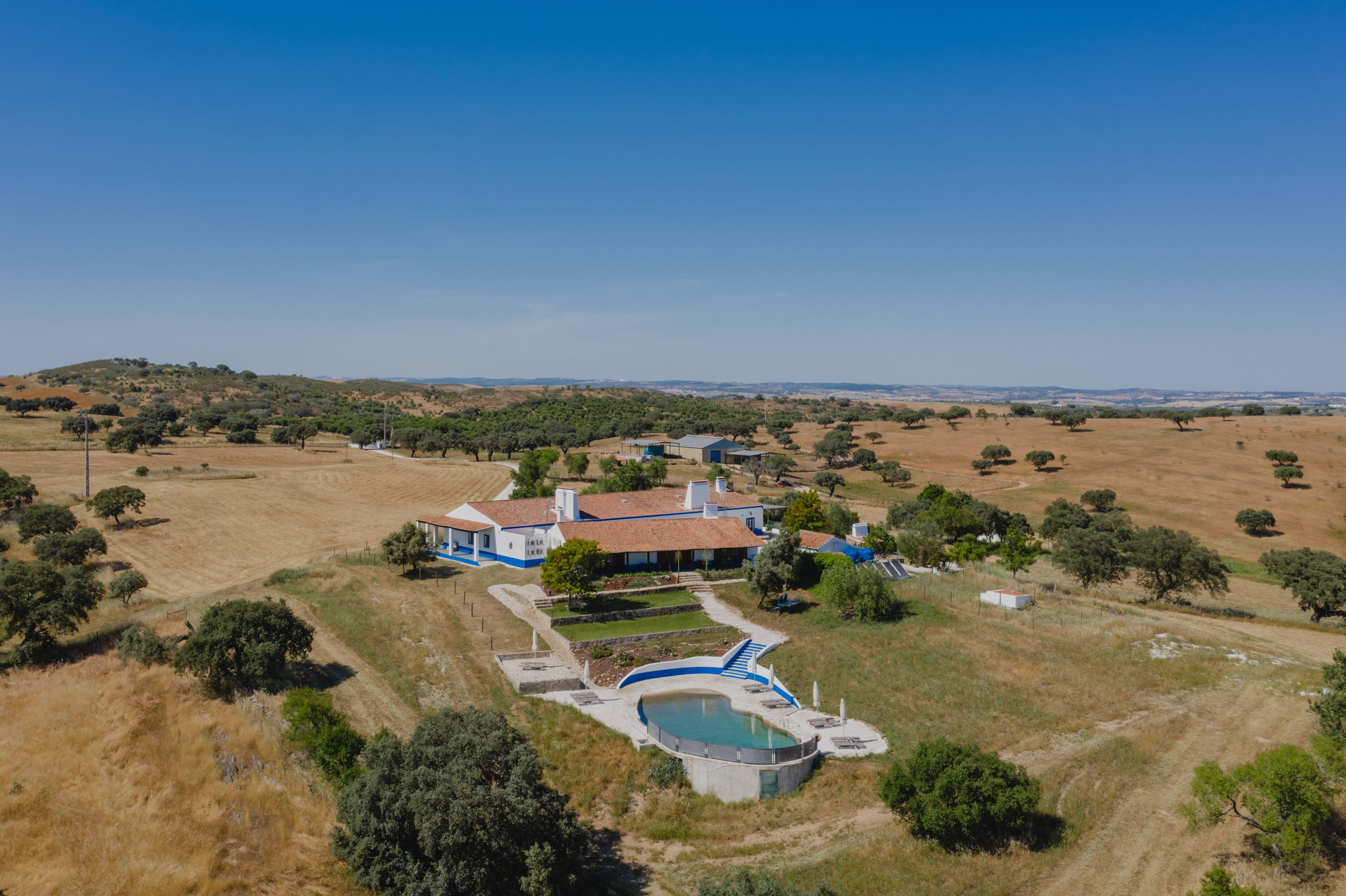 Vue aérienne d’une propriété comprenant une grande maison, une piscine et un paysage environnant.