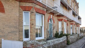 A row of terraced houses with brick facades, white window frames, and a stone wall with a metal fence. - 11a Market Cross Place (Aldeburgh)