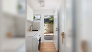 A narrow hallway with a kitchen on one side and a door leading to a garden.