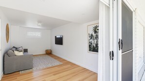 A spacious room with a grey sofa, a woven basket, and a framed picture on the wall.