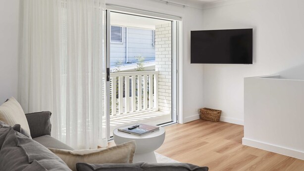 A modern living room with a sofa, a coffee table, and a TV mounted on the wall.