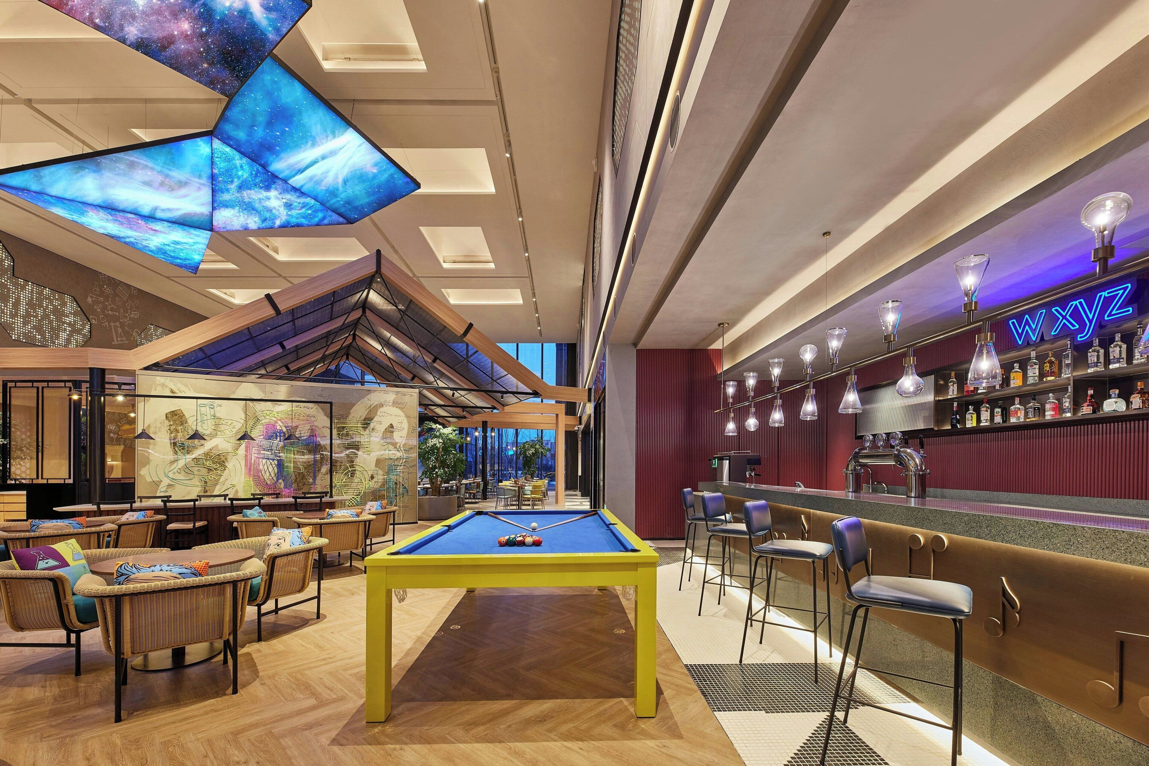 Ein Billardtisch in einer modernen Lounge mit Bar und Sitzgelegenheiten.