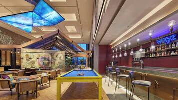 Ein Billardtisch in einer modernen Lounge mit Bar und Sitzgelegenheiten.
