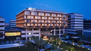 A modern hotel building with multiple floors, large windows, and a well-lit facade. - Aloft Beijing Huairou (Huairou)