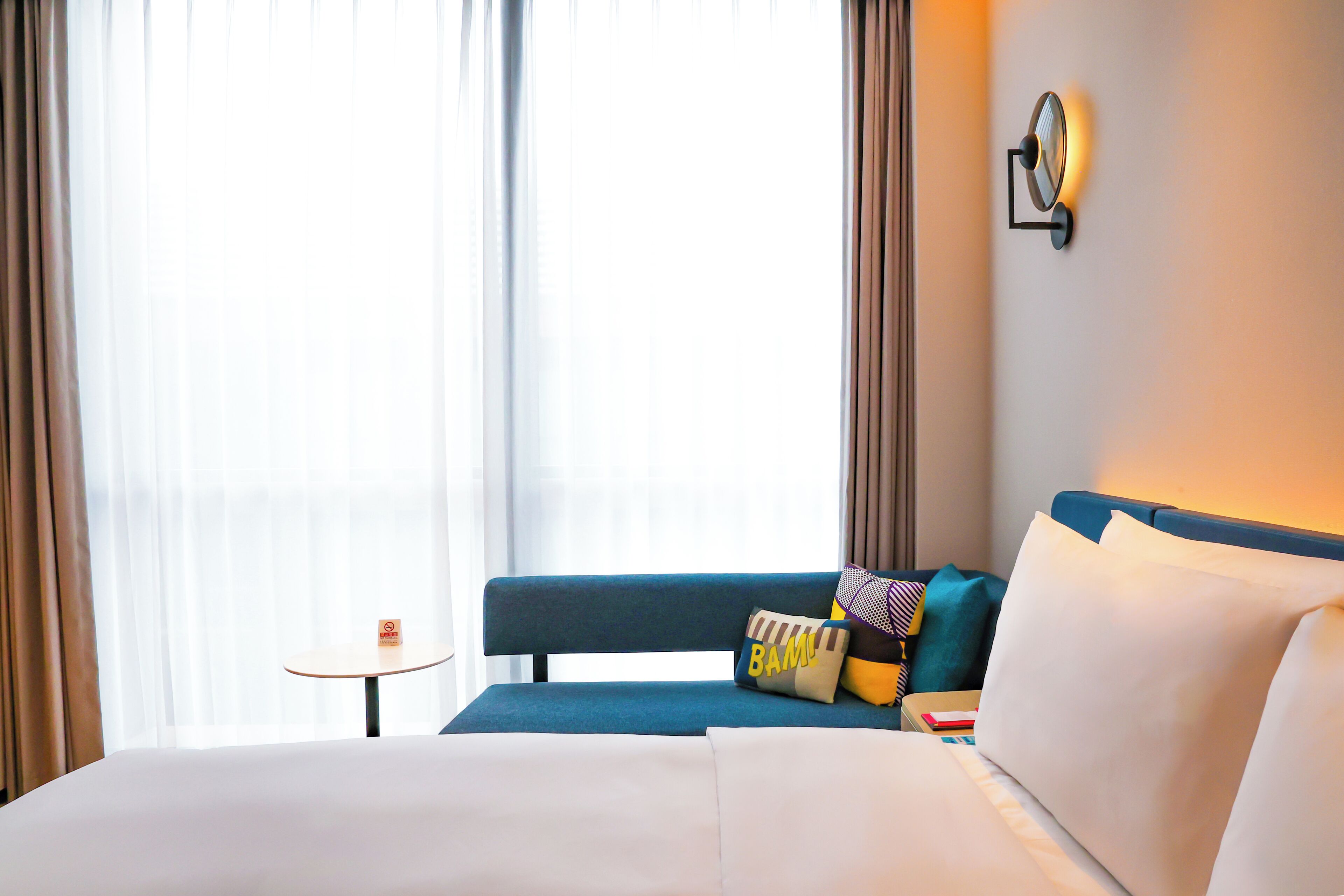 A hotel room with a bed, a blue sofa, and a small table.