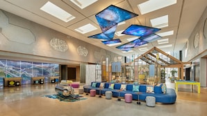 A spacious lobby with a blue sofa, a pool table, and a large digital display. - Aloft Beijing Huairou (Huairou)