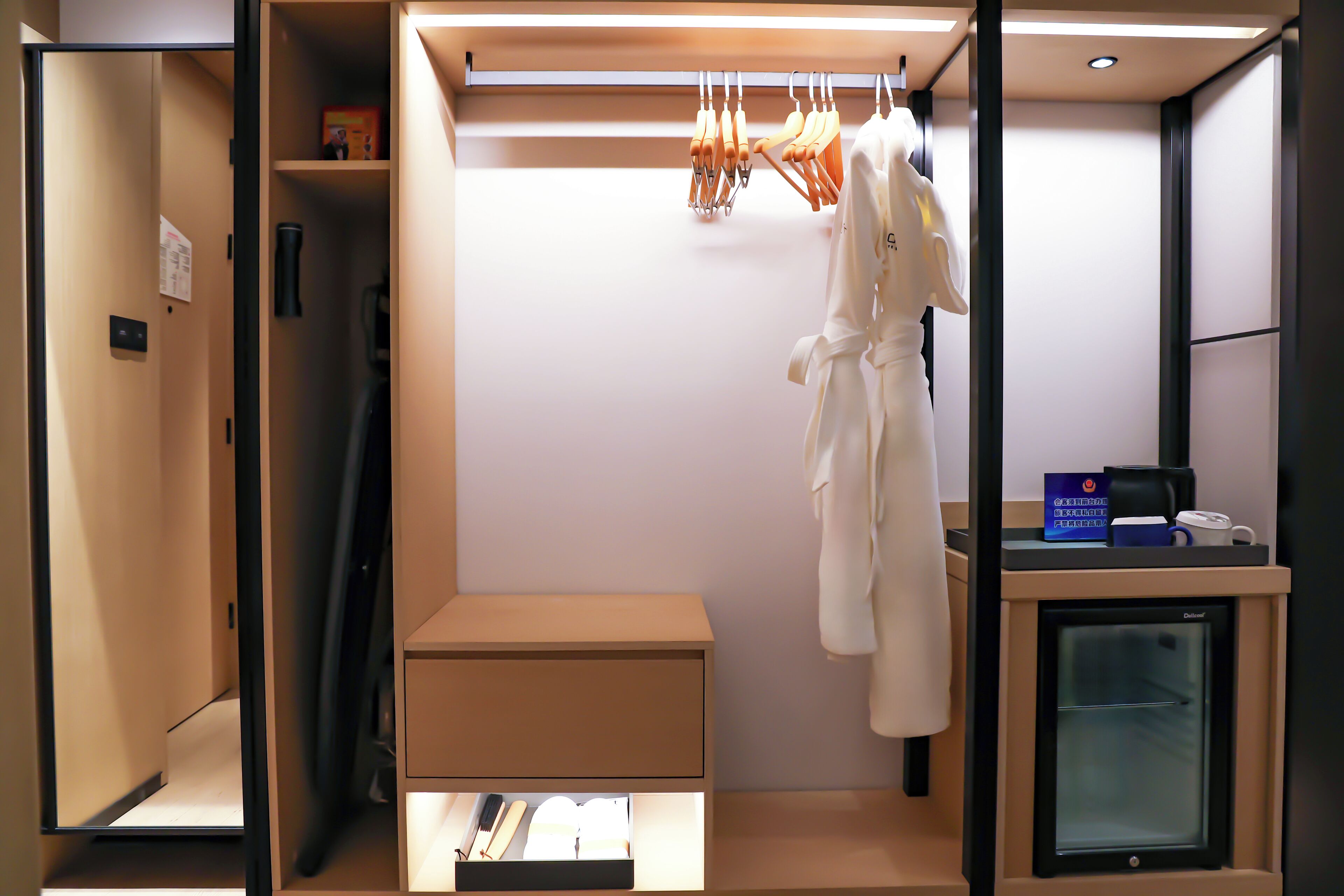 A hotel room with a walk-in closet, a minibar, and a small refrigerator.