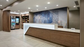 Un espace d’accueil d’hôtel au design moderne, comprenant un comptoir d’accueil en bois, un mur orné de texte et un distributeur automatique.
