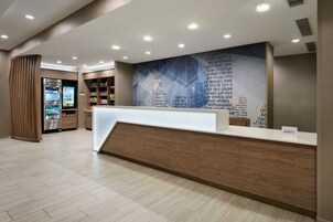 A hotel reception area with a modern design, featuring a wooden reception desk, a wall with text, and a vending machine.
