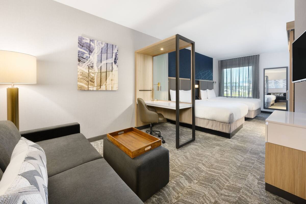 A modern hotel room with a sofa, a desk, a bed, and a dining table.