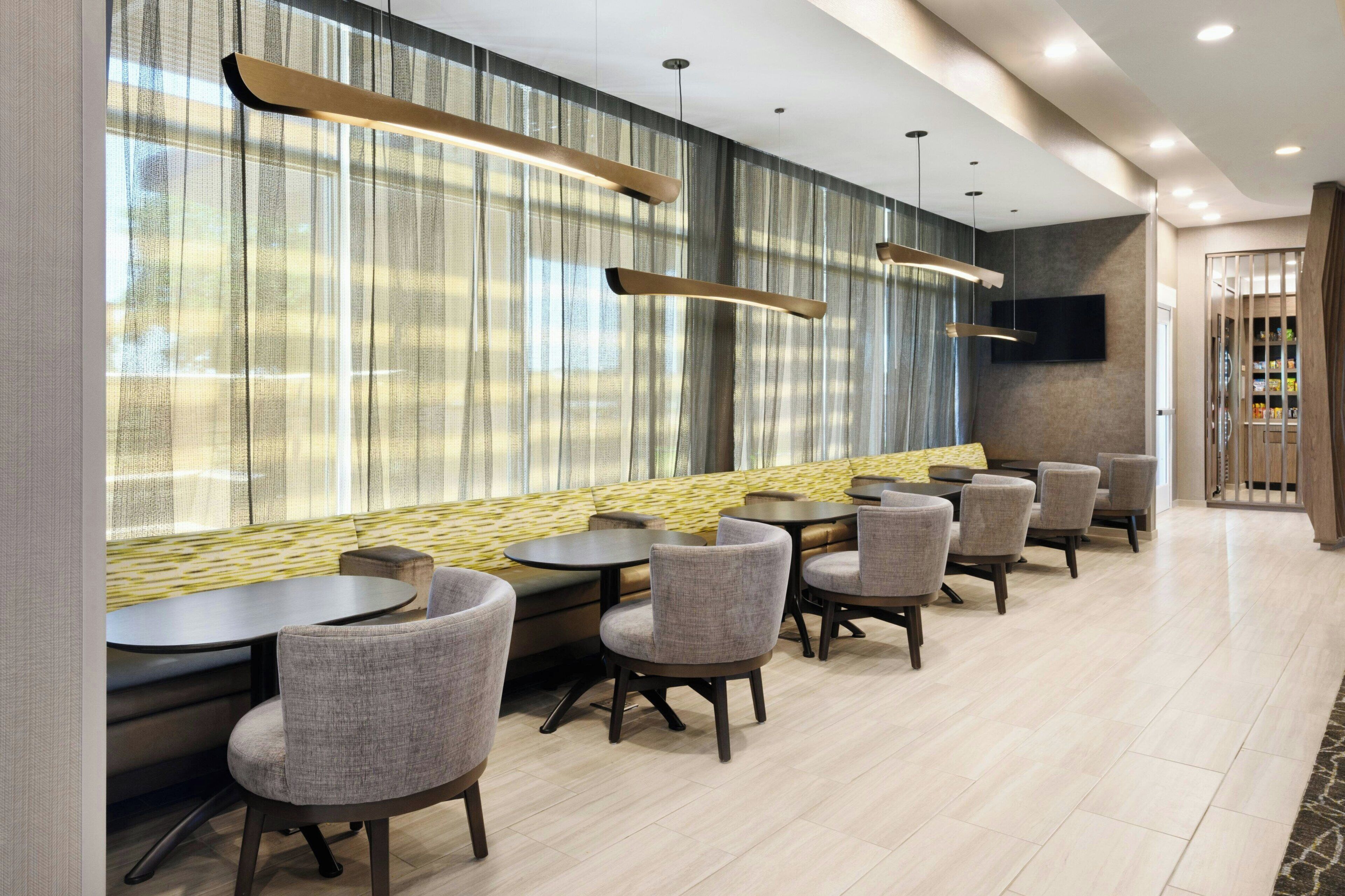 A modern restaurant with a long counter, cushioned seating, and pendant lighting.