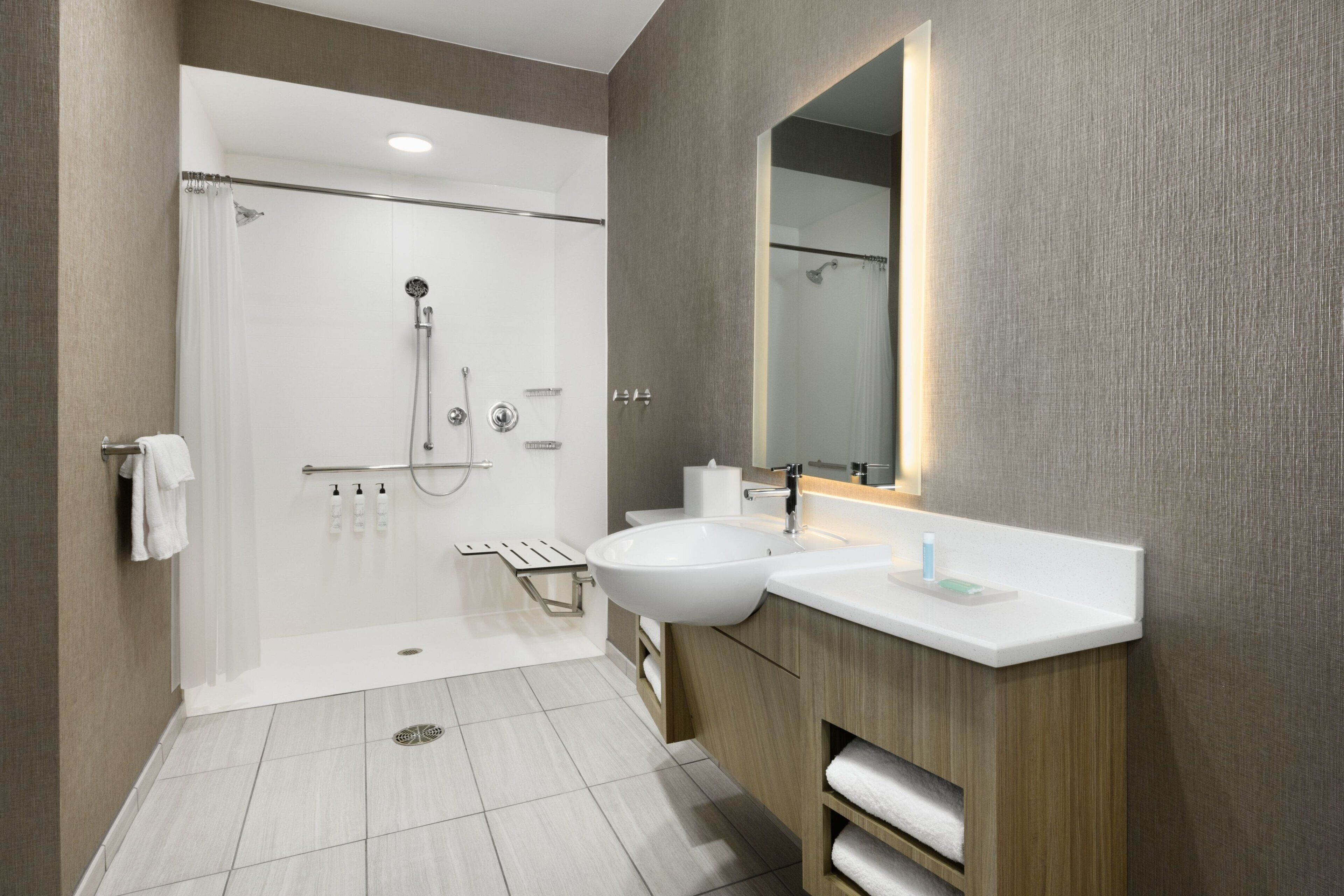A modern bathroom with a shower, sink, and mirror.