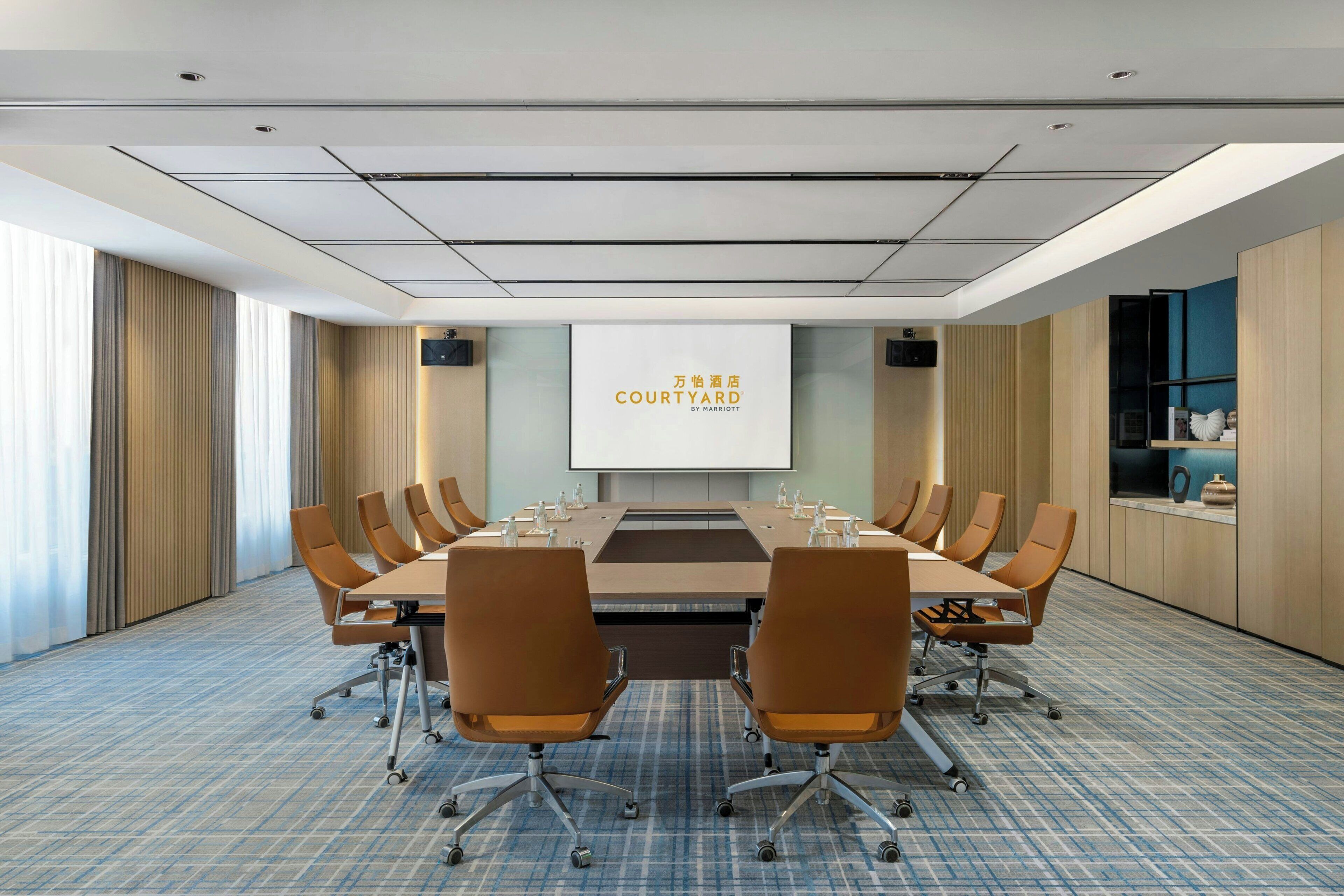 Une salle de conférence équipée d’une grande table, de plusieurs chaises et d’un écran de présentation.