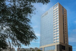 A tall, modern hotel with a glass facade and a sign reading "Courtyard." - Courtyard By Marriott Shanwei Haifeng (Shanwei)