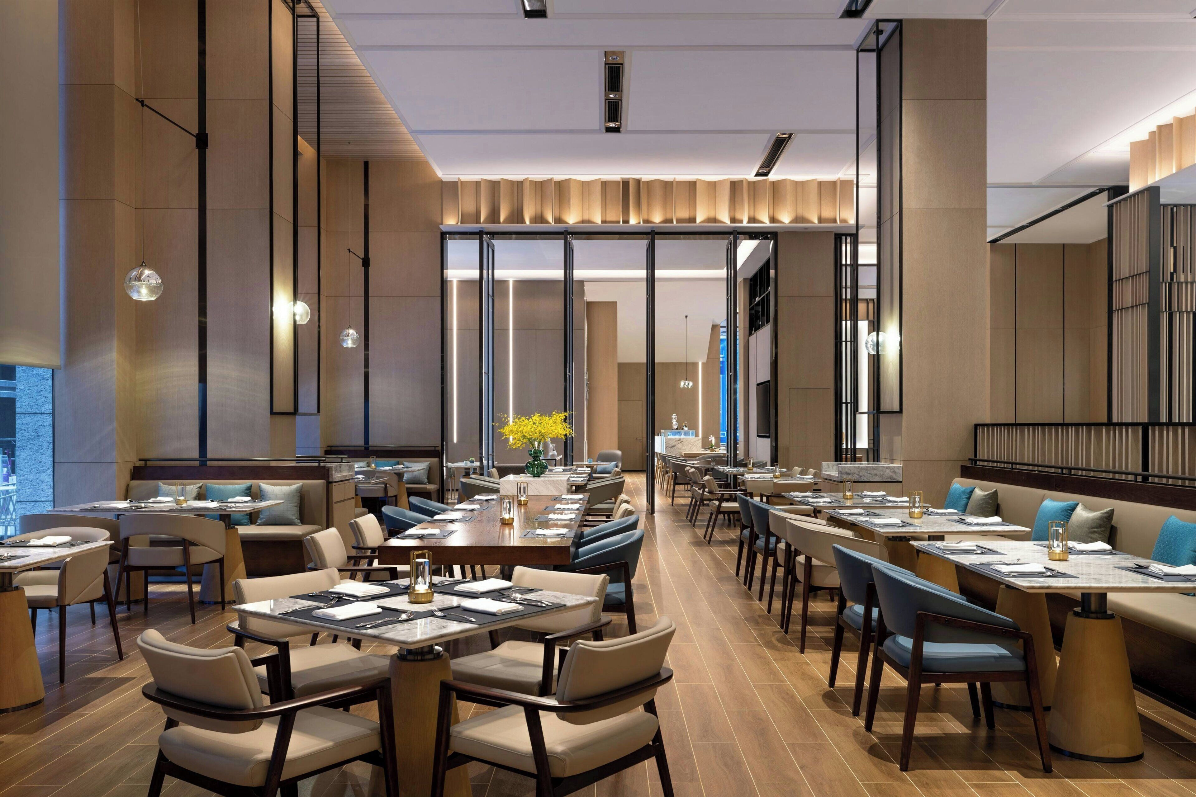 A modern dining area with long tables, comfortable seating, and a central decorative element.
