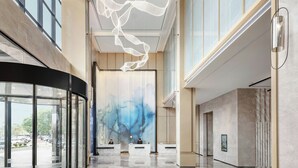 Un hall d’entrée spacieux, doté d’une entrée en verre incurvé, d’une grande fresque abstraite et d’un comptoir d’accueil.