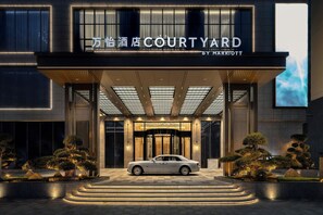 A modern hotel entrance with a car parked in front, featuring a large sign reading "COURTYARD BY MARRIOTT". - Courtyard By Marriott Shanwei Haifeng (Shanwei)