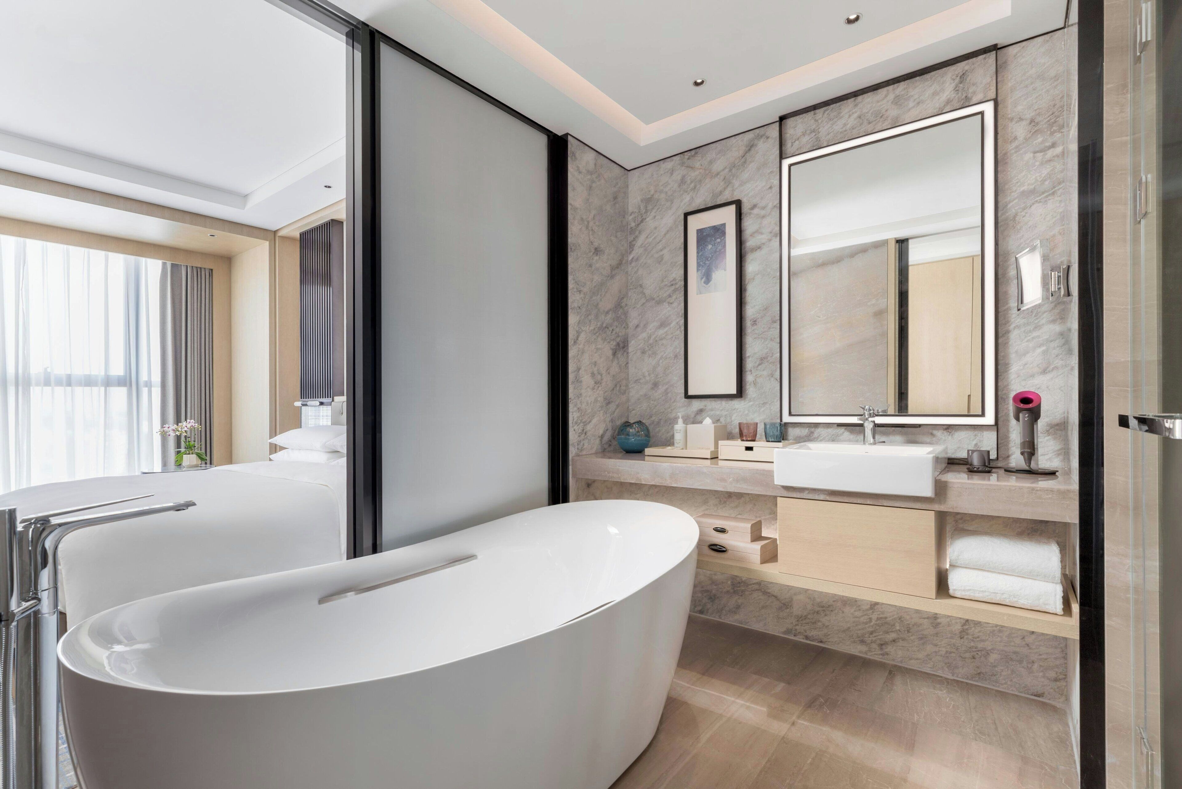 A modern bathroom with a freestanding bathtub, a large mirror, and a vanity with a sink.