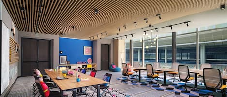 A modern meeting room with a wooden ceiling, large windows, and a colorful carpet.
