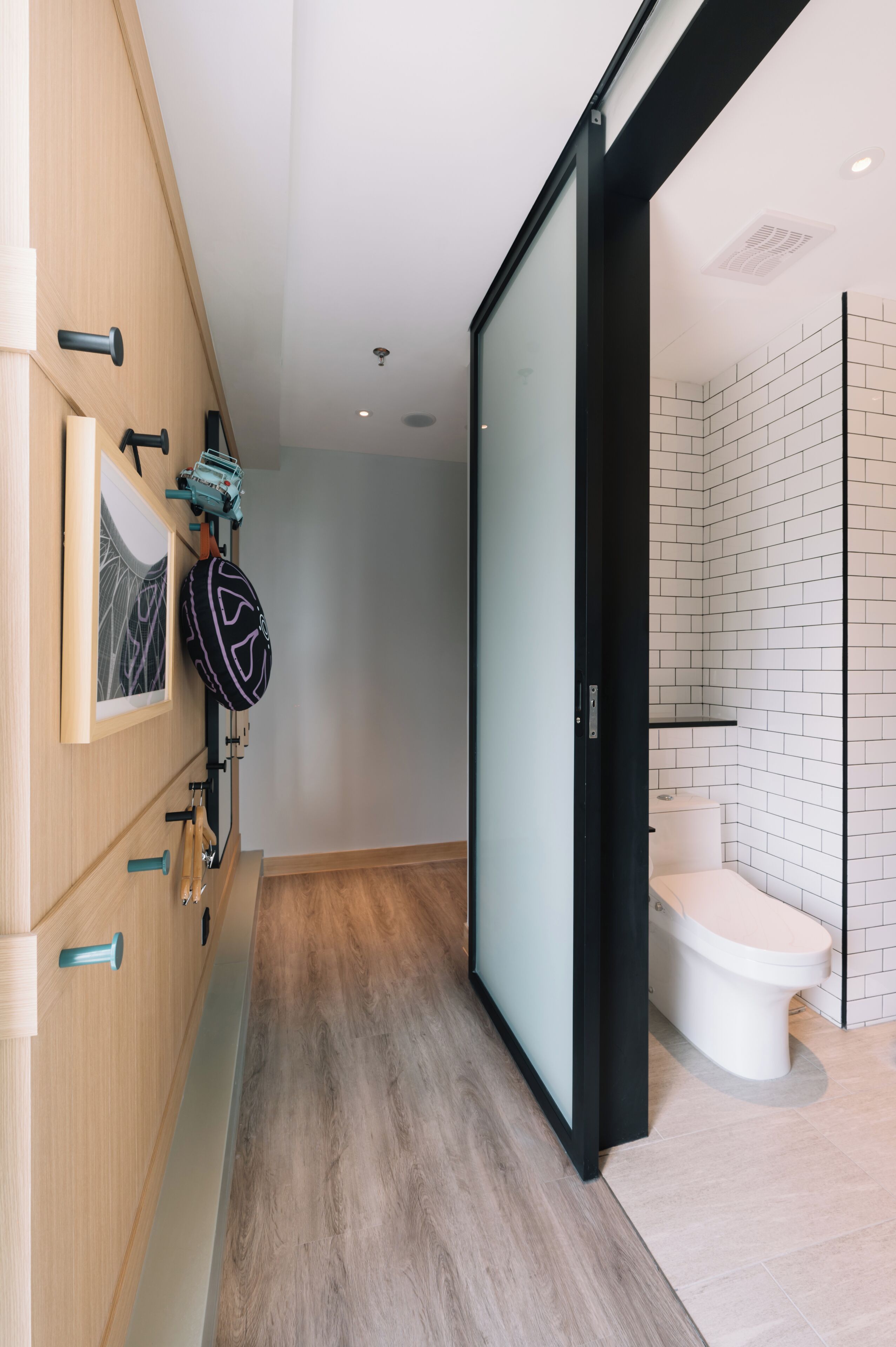 A modern bathroom with a toilet, a shower, and a wooden vanity with a mirror and a framed picture.